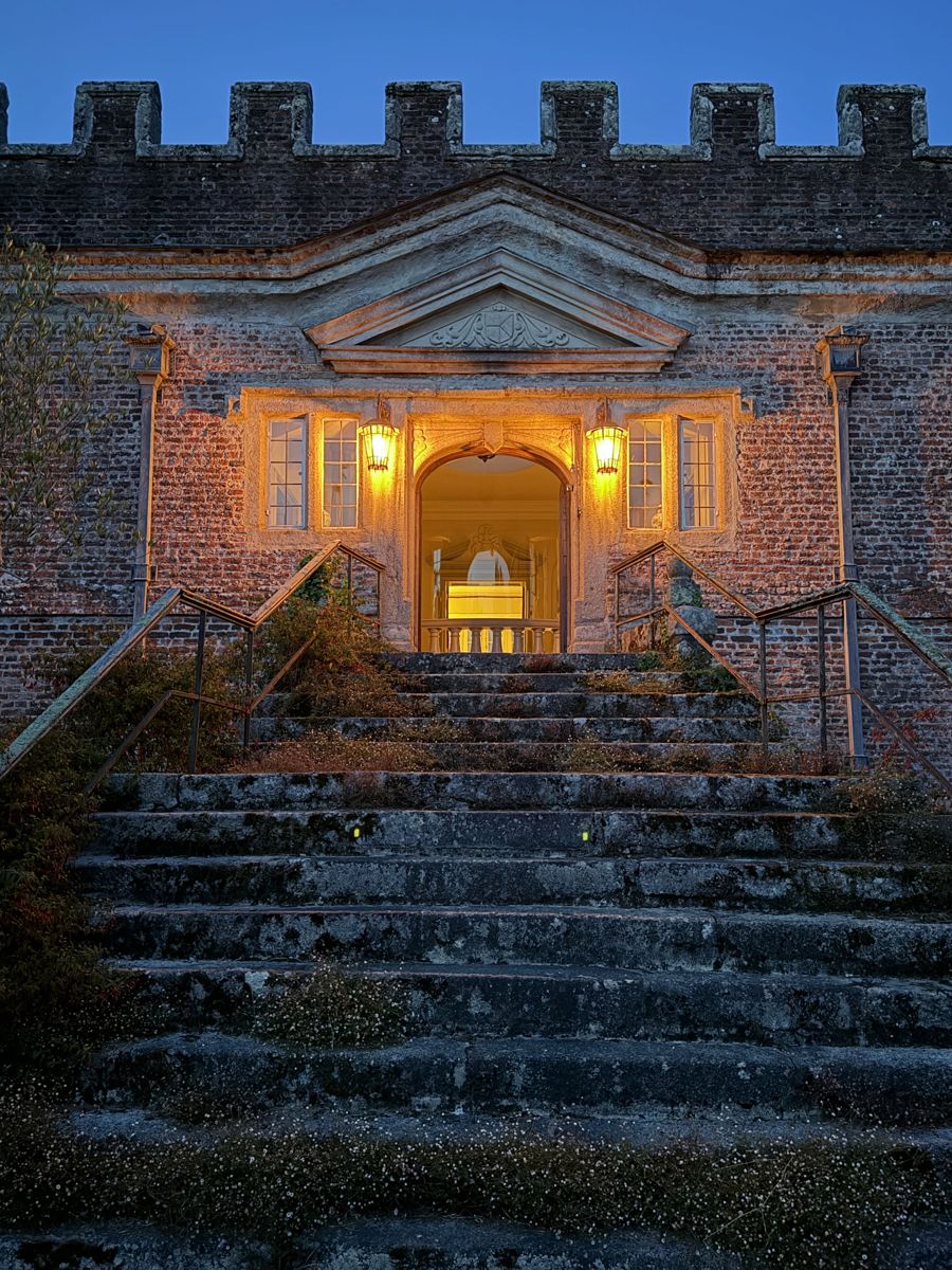 The front steps lit at dusk beneath the battlements
