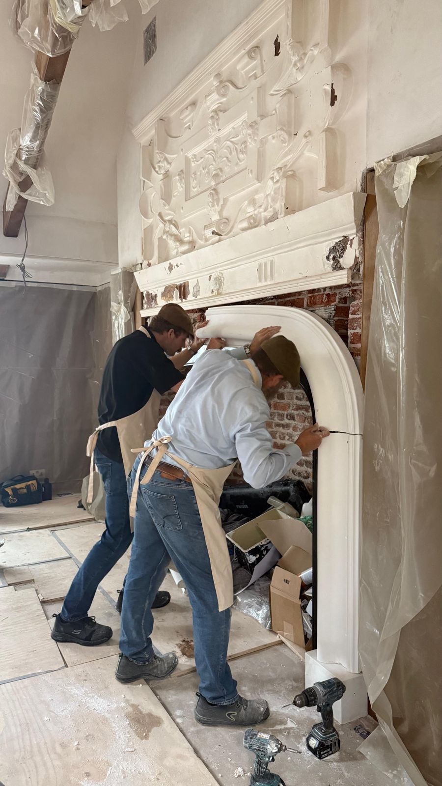 Plasterers fitting the new chimneypiece around the brick fireplace