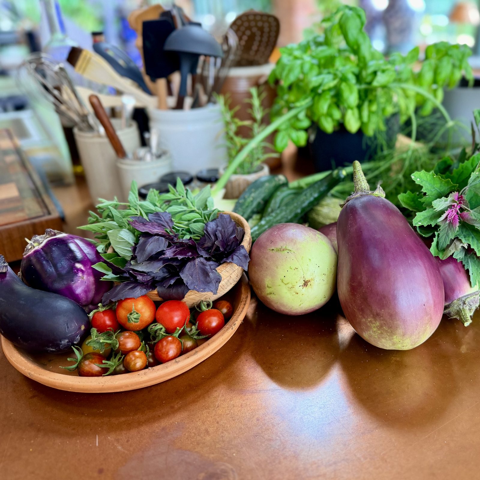 Aubergines, pears, tomatoes and herbs gathered on the kitchen table