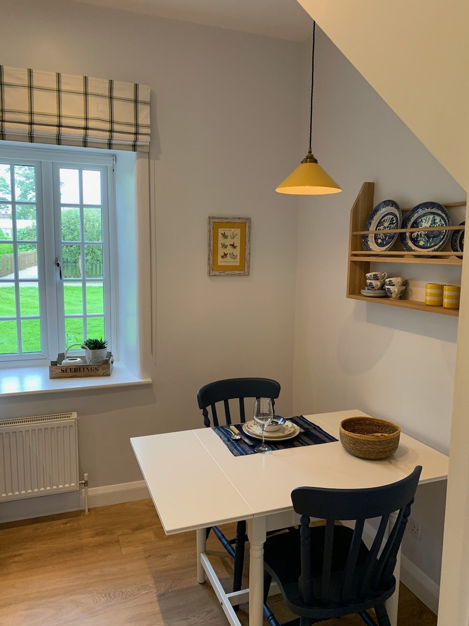 The kitchen table by the window, with a dresser shelf of blue-and-white china