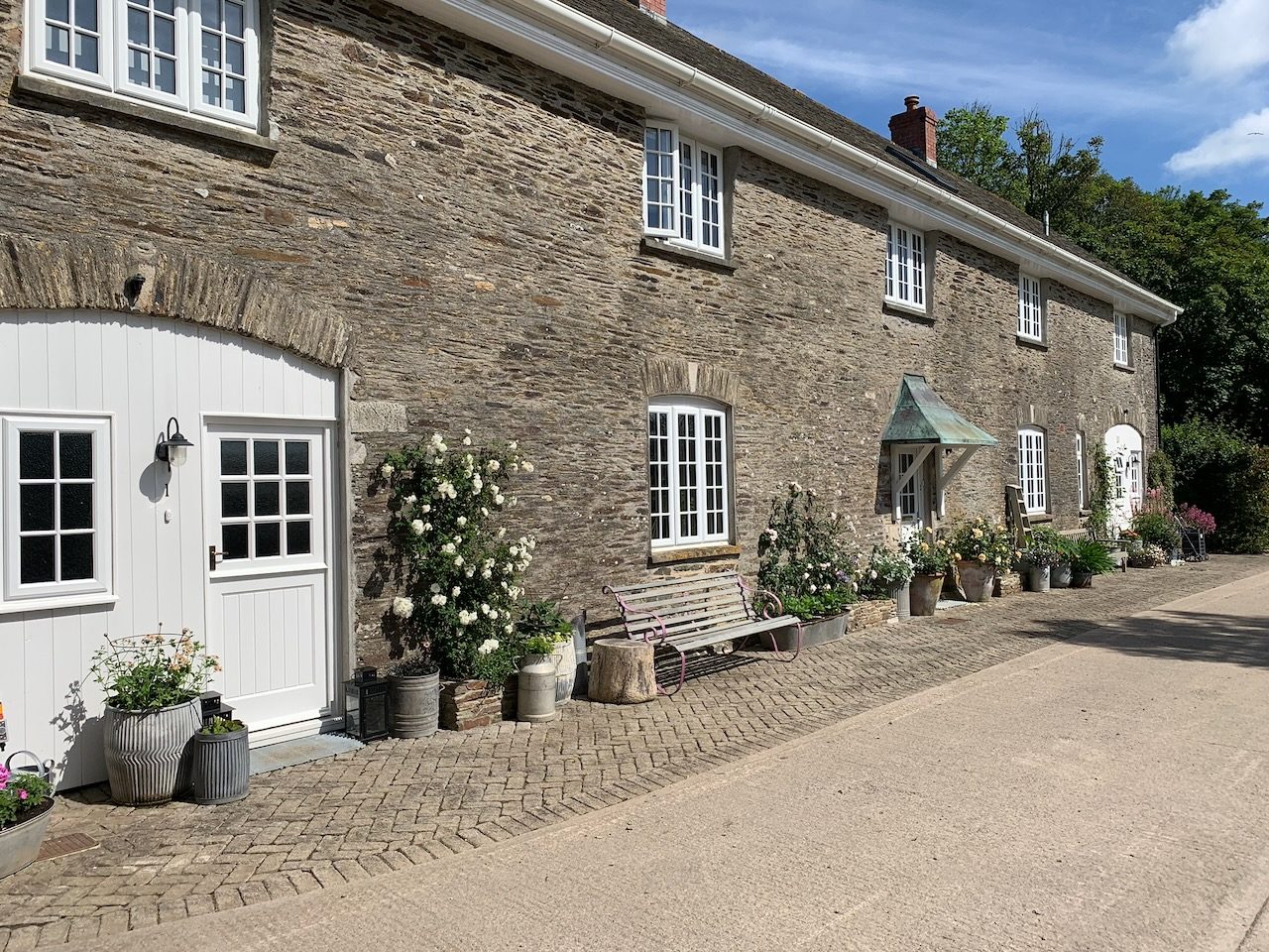 The stable range, with its arched white doors and pots along the cobbled path