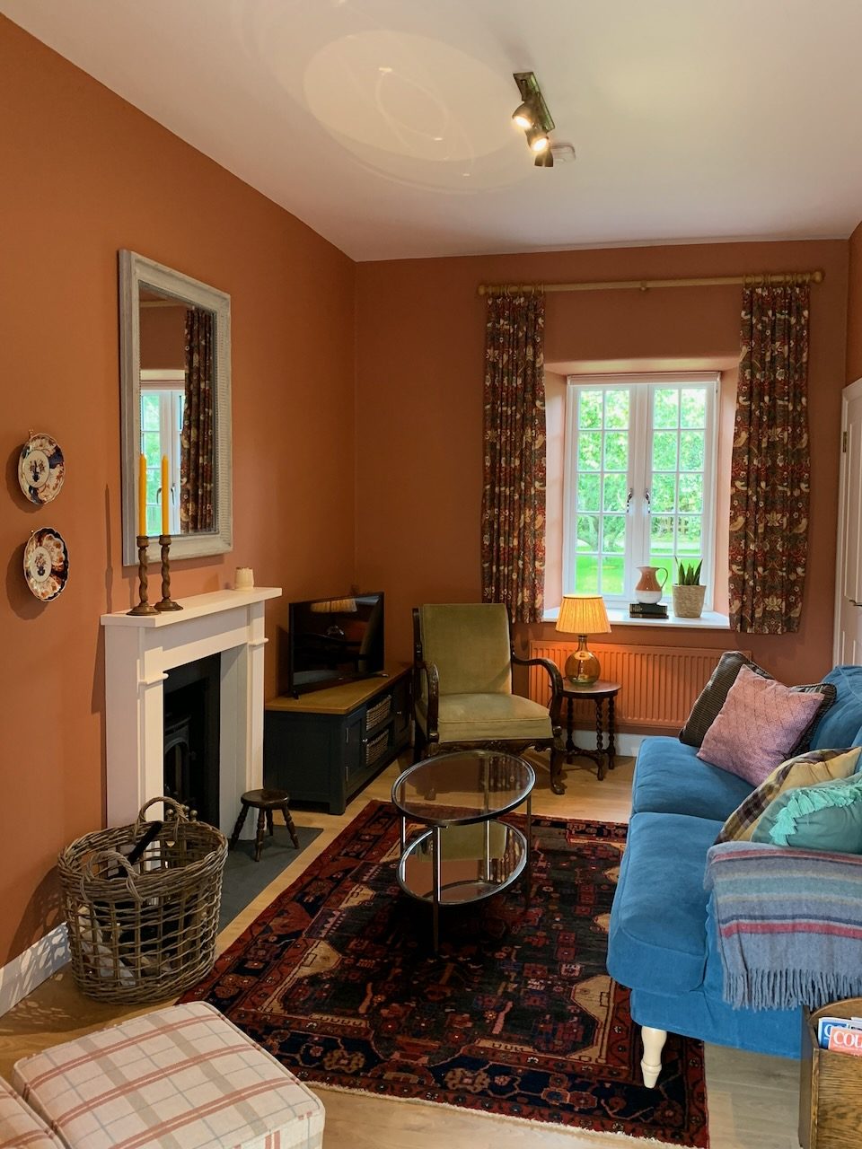 The sitting room, with terracotta walls, a fireplace and a blue sofa