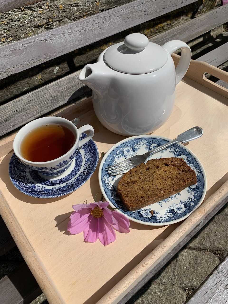 A tray of tea and cake on the bench outside
